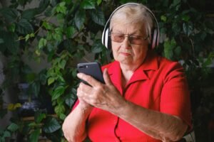 older woman using a headset and looking at the phone