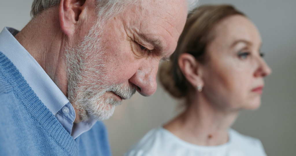 senior's face with a beard looking down next to a younger woman thinking on the challenges of aging