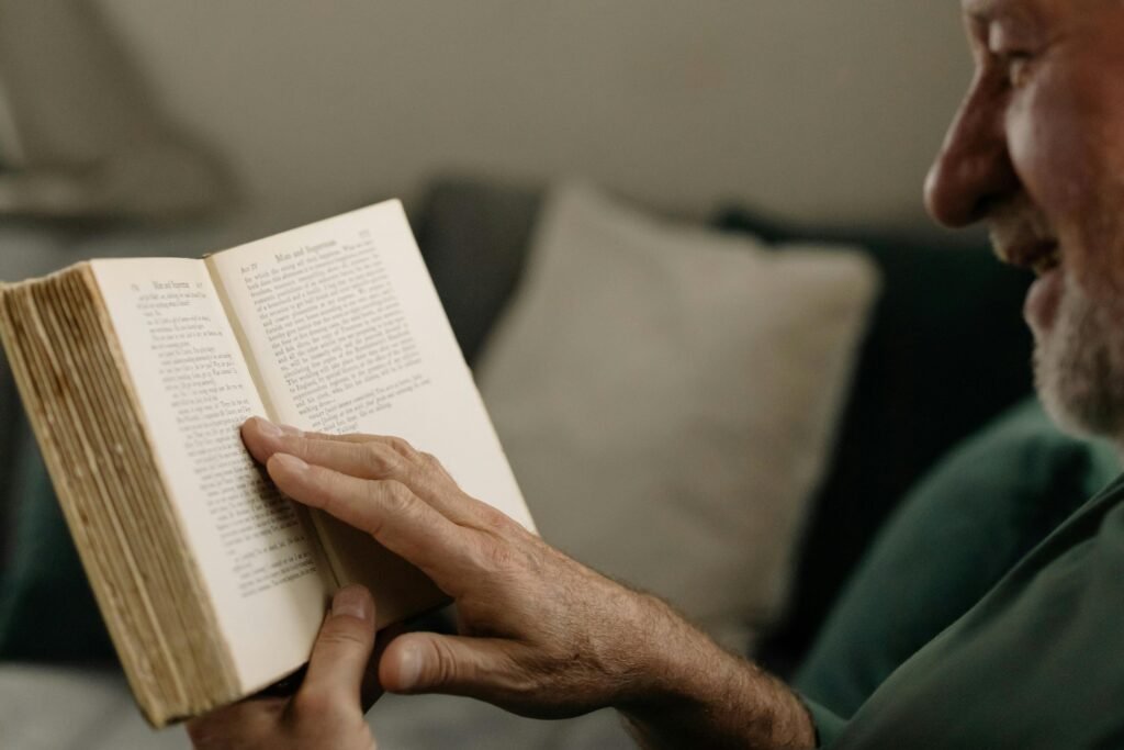 an older man is smiling while reading a book