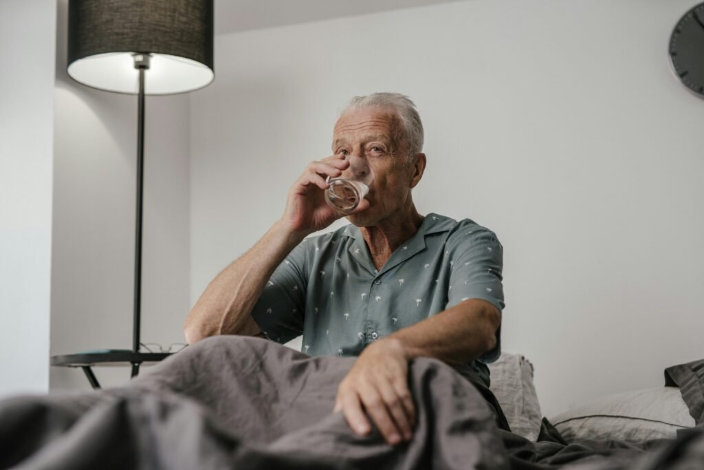 senior in bed drinking a glass of water to stay hydrated