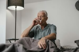 senior in bed drinking a glass of water to stay hydrated