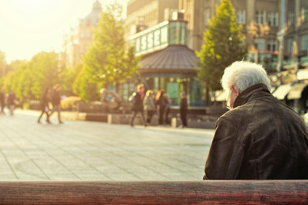 senior siting on a bench looking at people in an afternoon