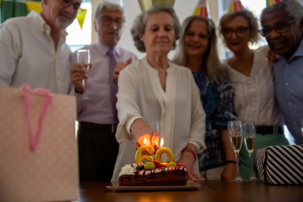 A group of older ladies and gentlemen standing around a cake. celebrating in a senior living facility.