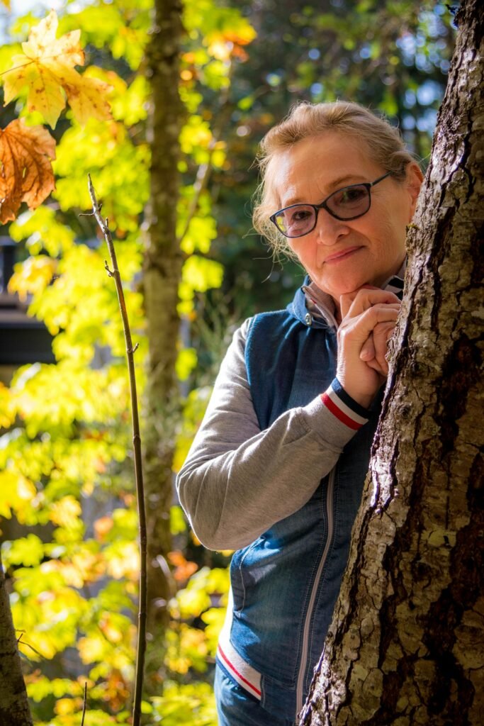 woman wearing glasses behind a tree