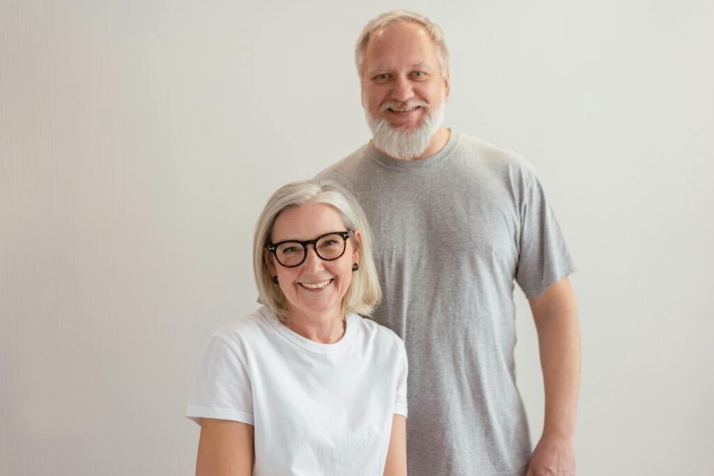 older couple, a woman with black glasses and whit t shirt and a man with a beard and grey t shirt